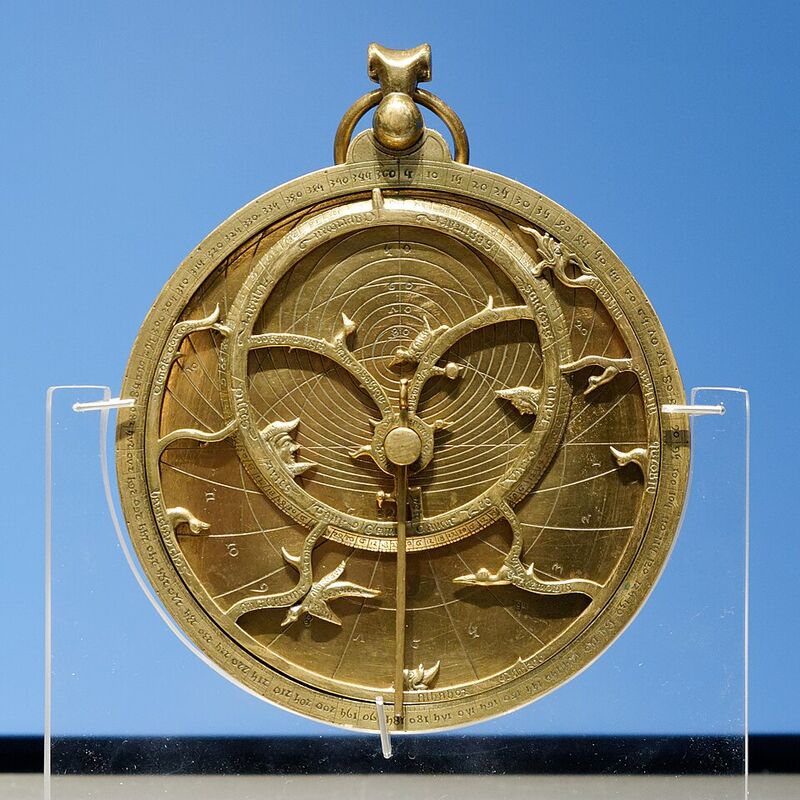 Astrolabe en laiton suspendu, avec une araignée ajourée aux pointes en forme de feuilles et une règle posée en travers.