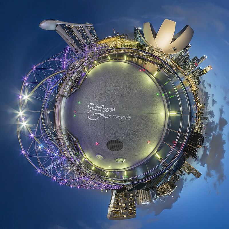 Photographie circulaire d'une baie urbaine de nuit : le sol forme un petit disque au centre, les gratte-ciel rayonnent tout autour vers l'extérieur et le ciel bleu entoure l'ensemble.