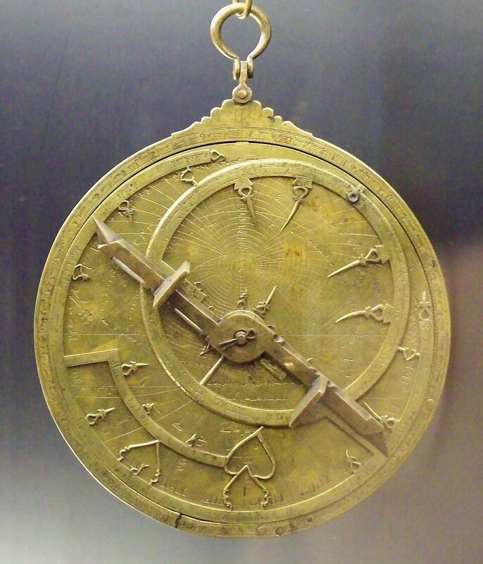 Astrolabe en laiton doré sur fond bleu nuit : une araignée ajourée aux motifs courbes recouvre un tympan gradué.