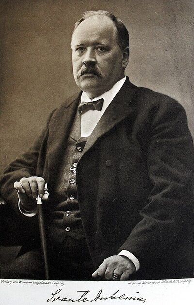 Photogravure en noir et blanc : portrait d'un homme moustachu en costume sombre, cheveux courts, regardant de trois quarts.