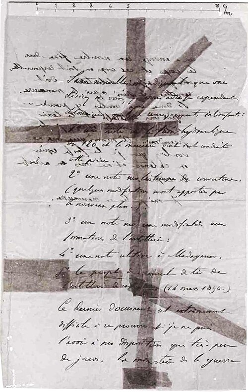 Photographie d'une lettre manuscrite à l'encre, déchirée en morceaux puis recollée avec des bandes de papier collant, avec une règle graduée en haut.