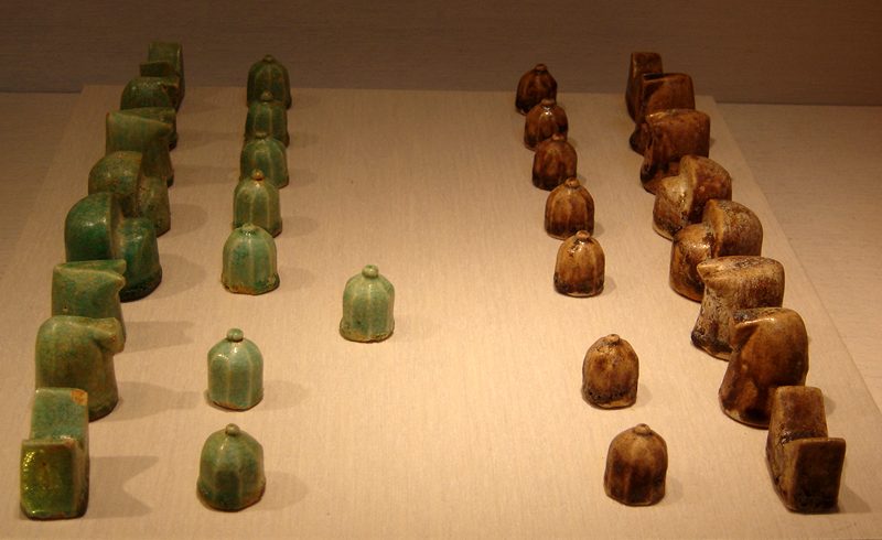 Pièces d'un jeu d'échecs ancien en céramique émaillée bleu turquoise, de formes stylisées, posées en rangées.