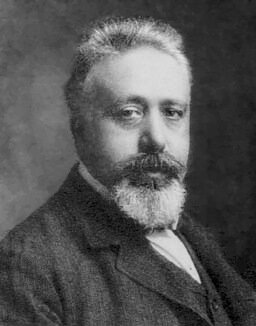 Portrait photographique en noir et blanc d'un homme à barbe, en costume.