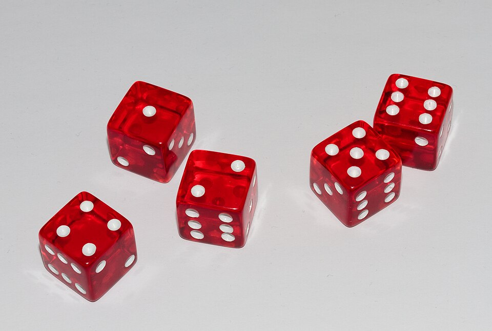 Cinq dés posés sur une table montrant les faces 1, 2, 4, 5 et 6.