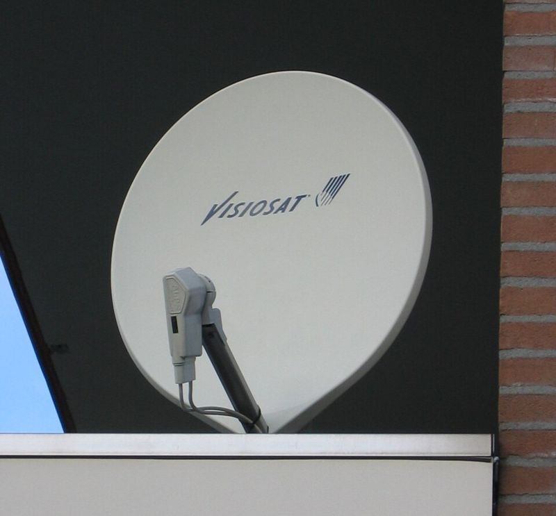 Une antenne de télévision décentrée, ovale, avec sa tête montée sur un bras en bas.