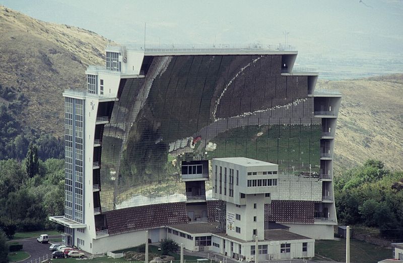 Le four solaire d'Odeillo : un immense miroir parabolique formé de milliers de petits miroirs, sur la façade d'un bâtiment.