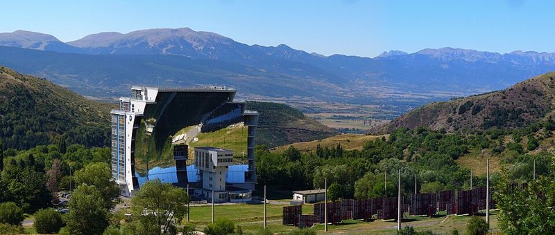 Vue d'ensemble du four d'Odeillo dans la montagne, avec les héliostats en terrasses devant la parabole.