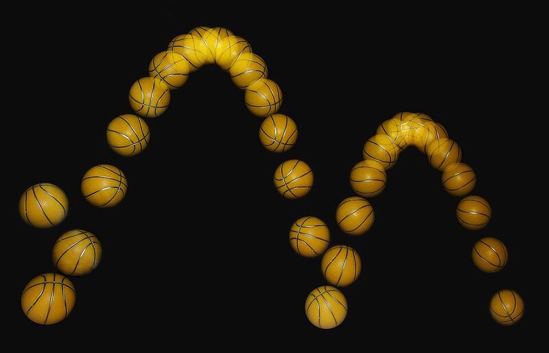 Photographie stroboscopique sur fond noir : un ballon jaune photographié à intervalles réguliers décrit deux arches successives, la seconde plus basse que la première.