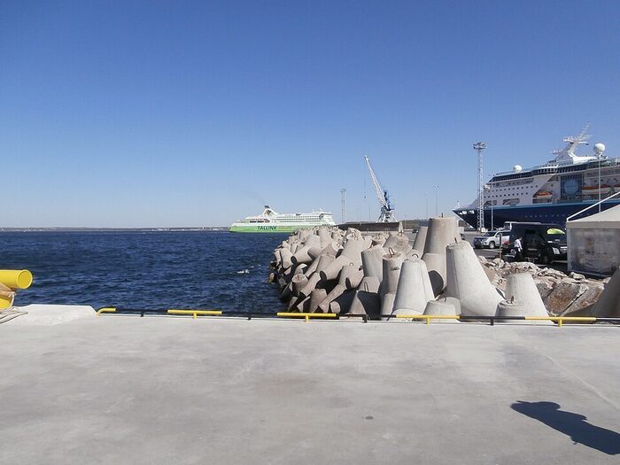 Enrochement de tétrapodes en béton gris, enchevêtrés au bord de l'eau dans un port.